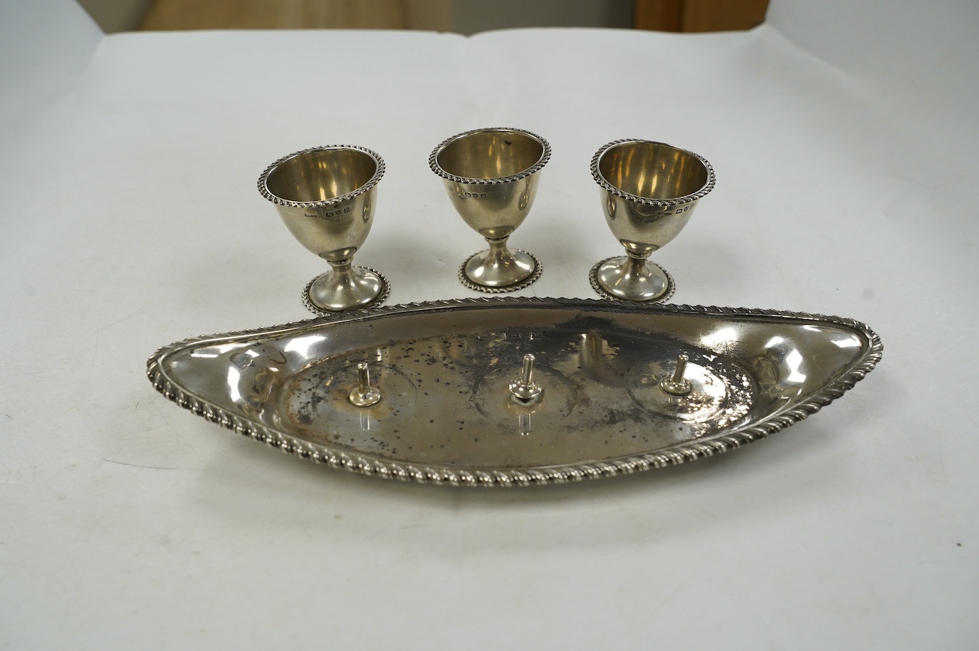 A late Victorian silver egg cruet, with three cups on a navette shaped stand, Chester, 1898, 25.8cm, 10.9oz. Condition - poor to fair